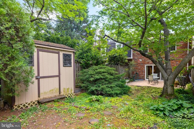 view of yard featuring a storage shed, fence, an outbuilding, and a patio area