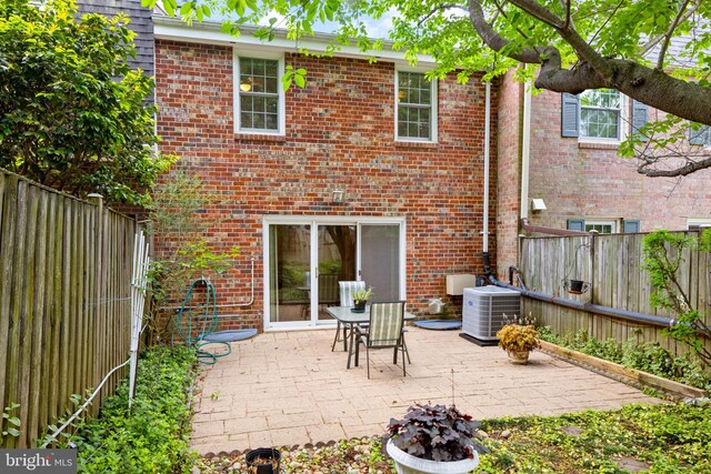 back of property with a fenced backyard, cooling unit, a patio area, and brick siding