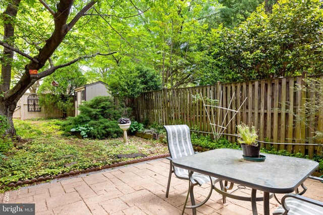 view of patio with an outbuilding, a fenced backyard, and a storage unit