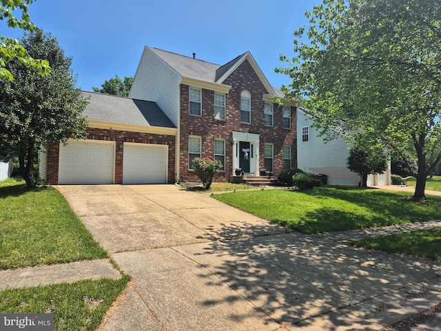 colonial home with an attached garage, concrete driveway, brick siding, and a front yard