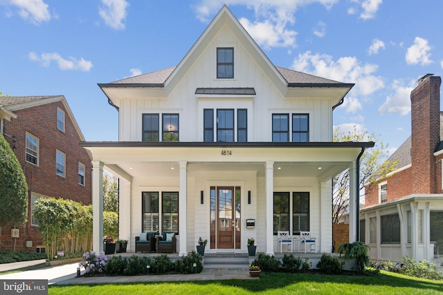 modern farmhouse featuring covered porch, board and batten siding, and a front yard