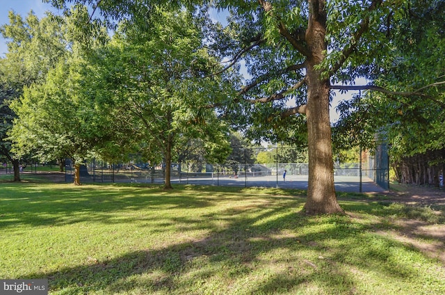 view of yard with a tennis court and fence
