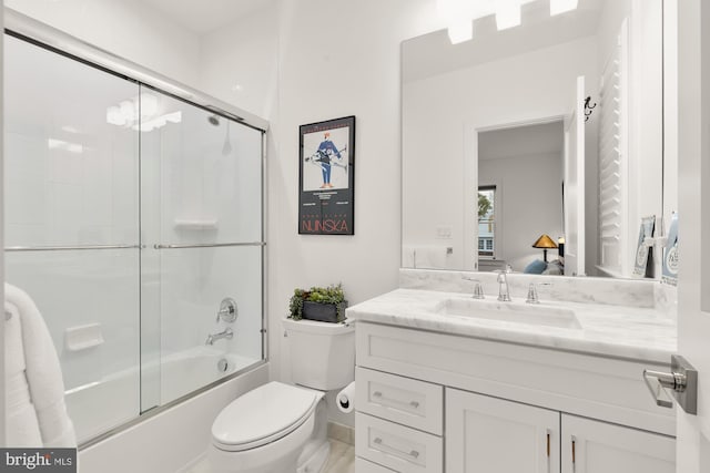 full bathroom with ensuite bathroom, combined bath / shower with glass door, toilet, and vanity