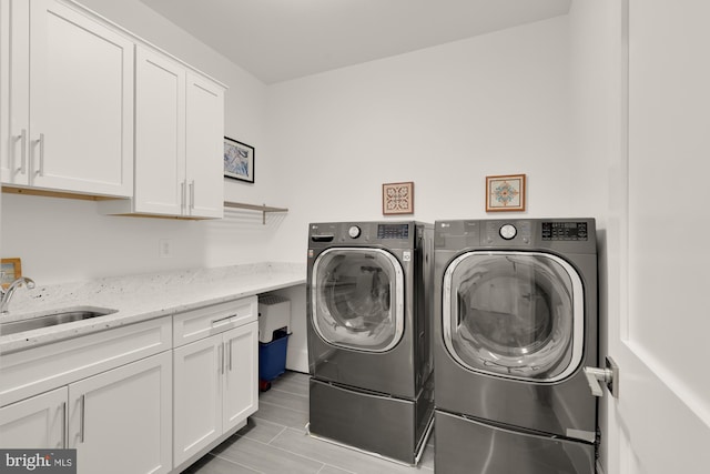 clothes washing area featuring a sink, cabinet space, and washer and clothes dryer