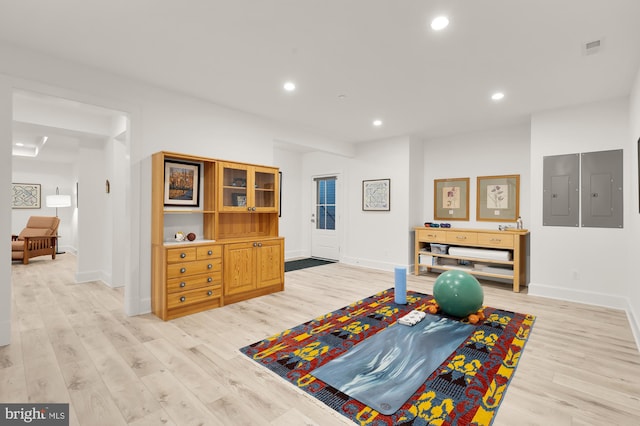 workout room featuring baseboards, electric panel, and light wood-style flooring