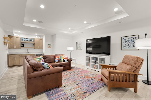 living room featuring a raised ceiling, baseboards, recessed lighting, and wet bar