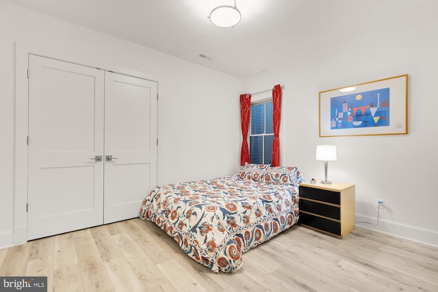 bedroom featuring a closet, baseboards, visible vents, and light wood-type flooring