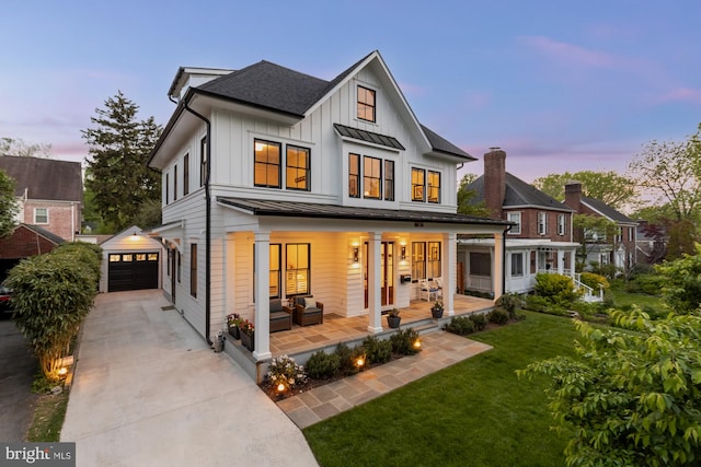 back of house at dusk with an outdoor structure, a garage, an outdoor hangout area, board and batten siding, and driveway