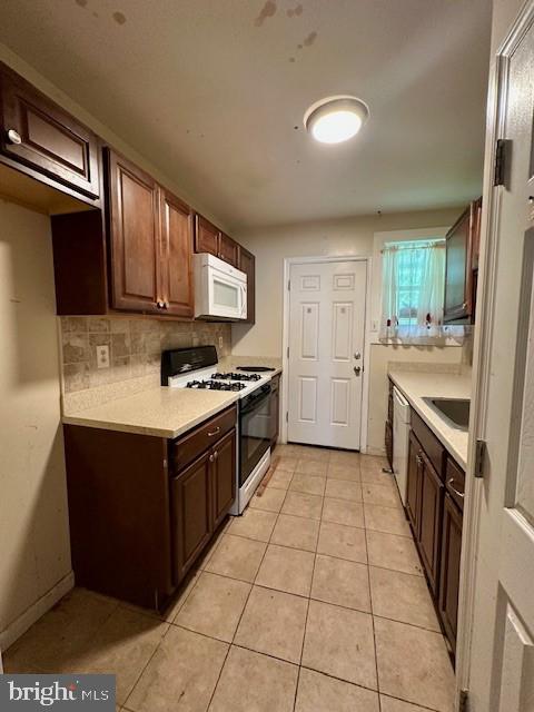 2407 Matthew Henson, Landover, MD 20785 - kitchen featuring dark brown cabinets, white appliances, light tile patterned flooring, decorative backsplash, and light countertops