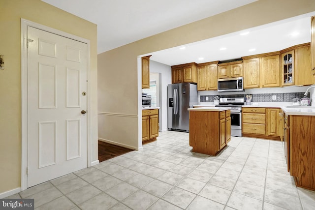 7117 Stanchion Ln, Burke, VA 22015 - kitchen featuring appliances with stainless steel finishes, a kitchen island, a sink, glass insert cabinets, and light countertops