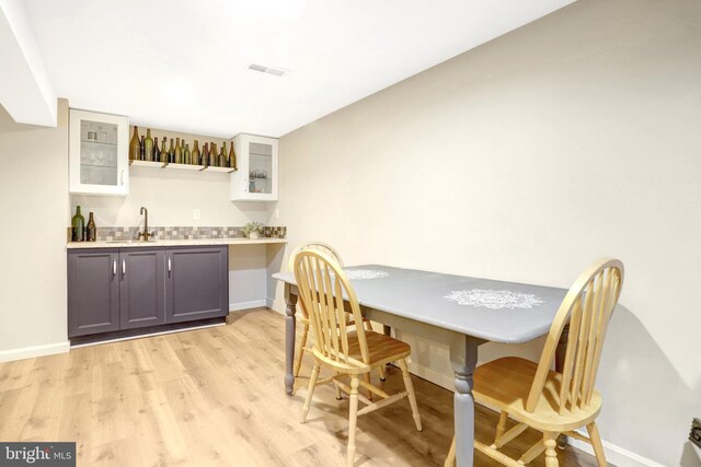 7117 Stanchion Ln, Burke, VA 22015 - dining space featuring bar with sink, baseboards, and light wood-style floors