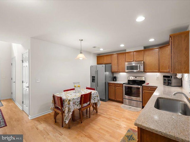 139 Gazebo Ln, Middletown, DE 19709 - kitchen with brown cabinets, a sink, light wood-type flooring, light stone countertops, and appliances with stainless steel finishes