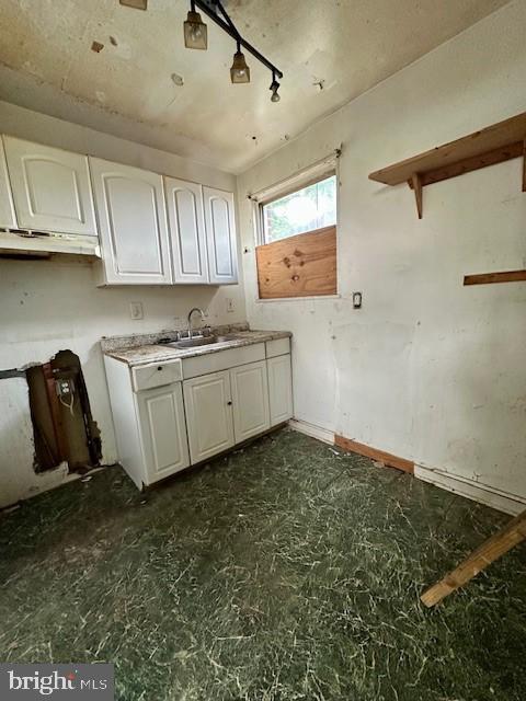 kitchen with a sink, open shelves, white cabinetry, and light countertops