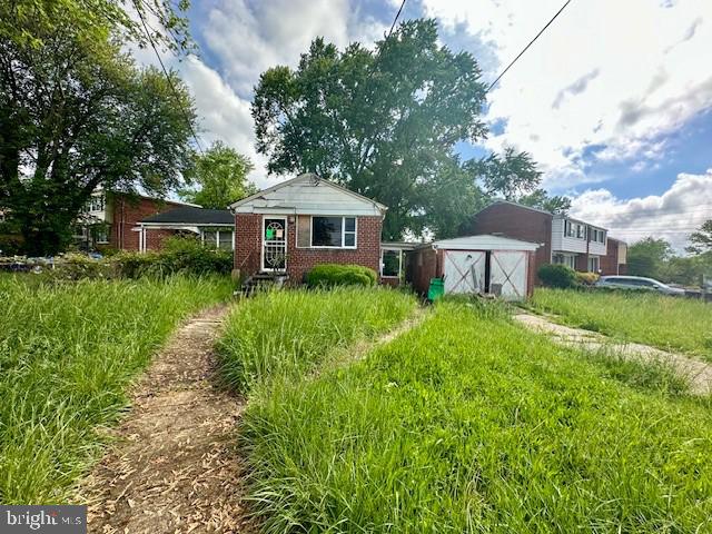 back of house featuring a shed, brick siding, a garage, and an outdoor structure