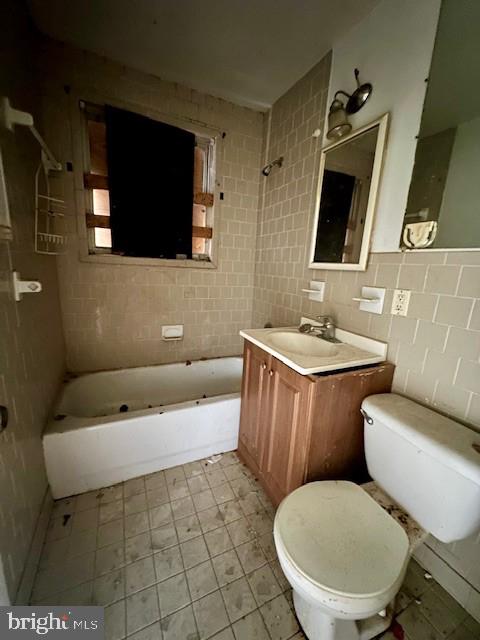 full bath with bathing tub / shower combination, tile walls, toilet, and vanity