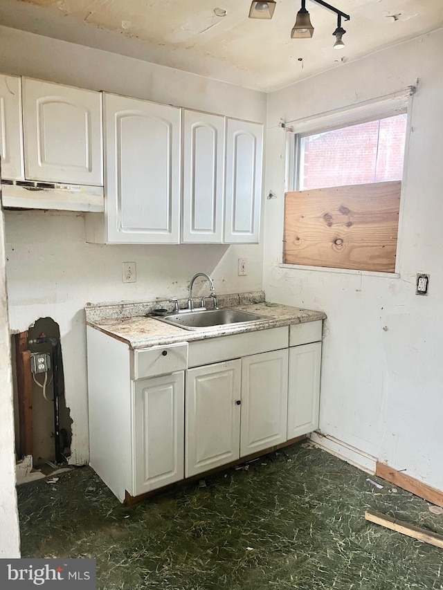 kitchen with under cabinet range hood, white cabinetry, a sink, and light countertops