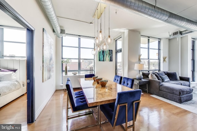 dining room with light wood-style floors, a healthy amount of sunlight, baseboards, and visible vents
