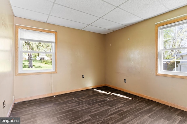 unfurnished room with baseboards, wood finished floors, and a paneled ceiling