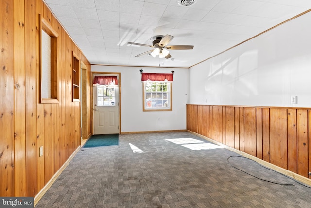 spare room with wooden walls, ceiling fan, wainscoting, carpet floors, and baseboards