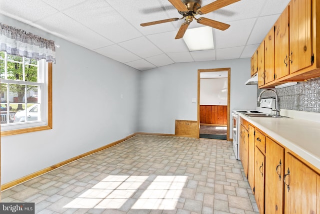 kitchen featuring brick patterned floor, baseboards, a drop ceiling, white electric range, and light countertops