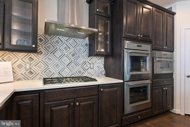 3419 Pocahontas Dr, Edgewater, MD 21037 - kitchen featuring wall chimney exhaust hood, dark brown cabinets, appliances with stainless steel finishes, and decorative backsplash