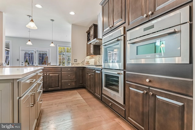 3419 Pocahontas Dr, Edgewater, MD 21037 - kitchen featuring stainless steel appliances, light countertops, dark brown cabinets, light wood finished floors, and pendant lighting
