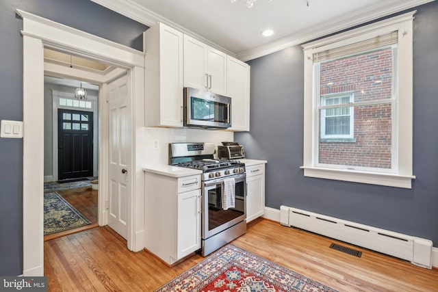 3213 Jocelyn St NW, Washington, DC 20015 - kitchen with appliances with stainless steel finishes, light wood-style flooring, a baseboard heating unit, ornamental molding, and white cabinetry