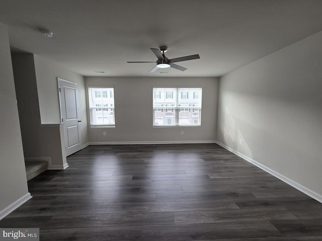 unfurnished room with baseboards, a ceiling fan, and dark wood-style flooring