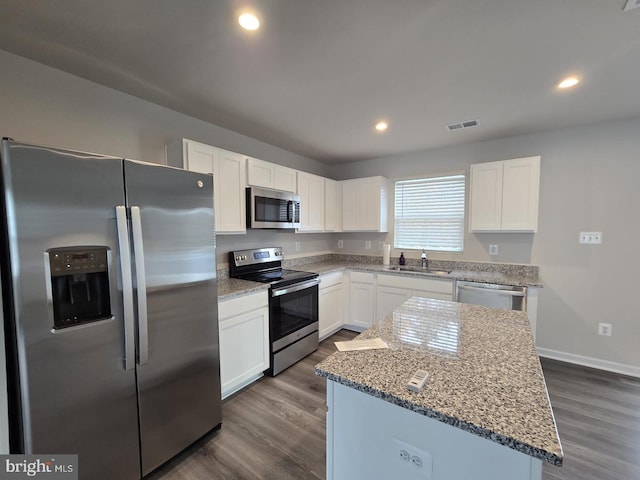 kitchen with dark wood-style flooring, visible vents, a sink, light stone counters, and stainless steel appliances