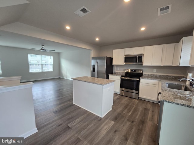 kitchen with visible vents, a kitchen island, light stone countertops, a sink, and stainless steel appliances