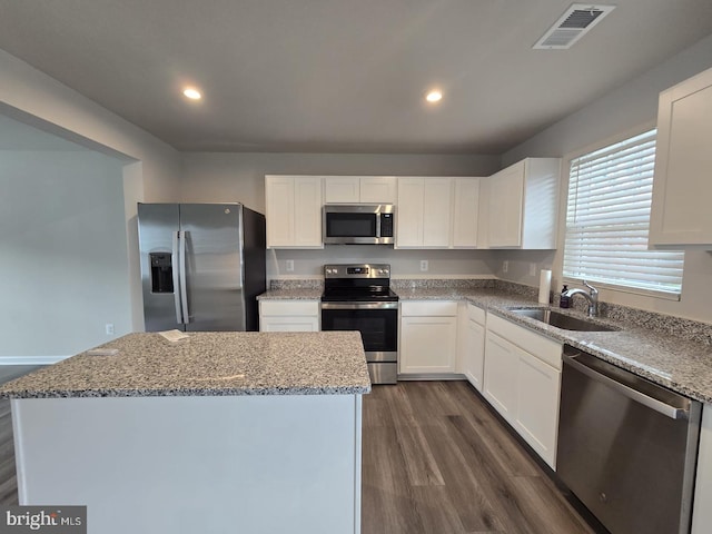 kitchen with white cabinets, light stone countertops, appliances with stainless steel finishes, a sink, and visible vents