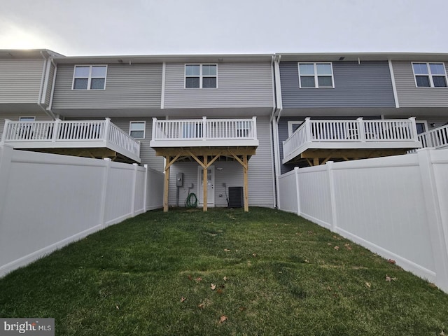 back of house with a fenced backyard and a yard