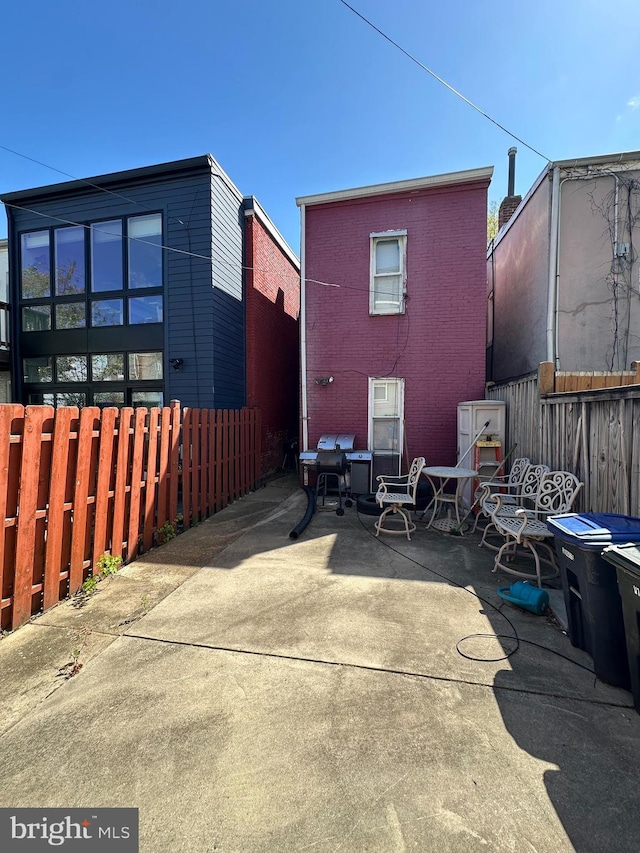rear view of house featuring brick siding, fence private yard, and a patio area