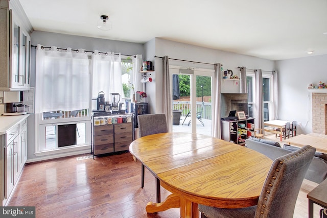 dining space with wood finished floors and a brick fireplace