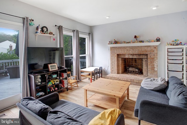 living room with light wood-type flooring and a brick fireplace
