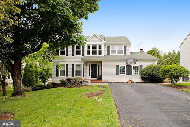 view of front of property featuring driveway, a front lawn, and a chimney