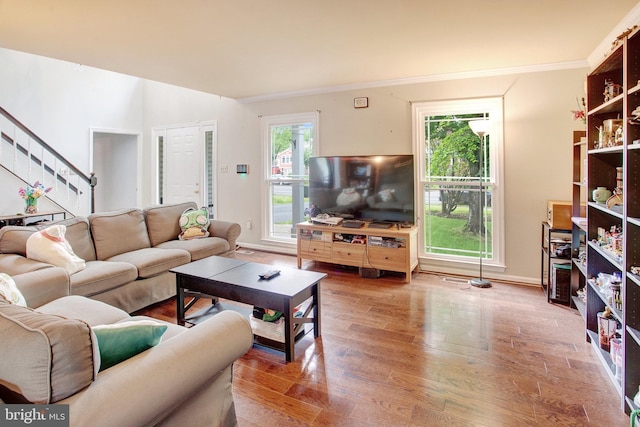 living room with stairway, wood finished floors, crown molding, and baseboards