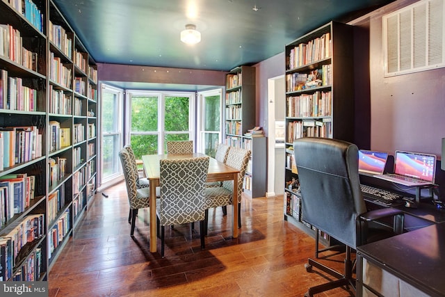 home office with wall of books and wood finished floors