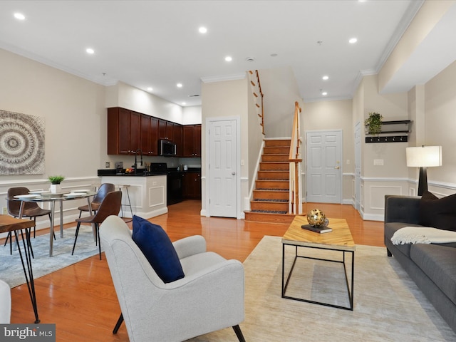 living area with crown molding, light wood finished floors, stairs, and recessed lighting