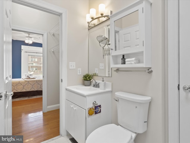 ensuite bathroom with connected bathroom, vanity, toilet, wood finished floors, and ceiling fan with notable chandelier