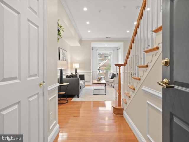 entrance foyer with light wood finished floors, recessed lighting, crown molding, stairs, and wainscoting