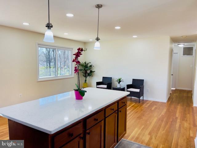 kitchen with hanging light fixtures, light countertops, and light wood-type flooring