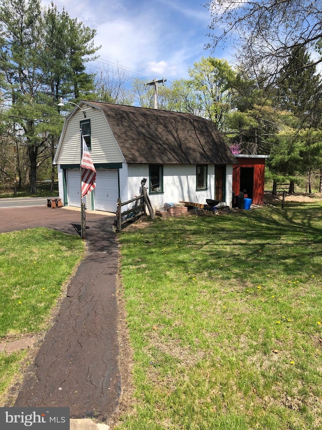 view of front of property with a gambrel roof, driveway, and a front yard