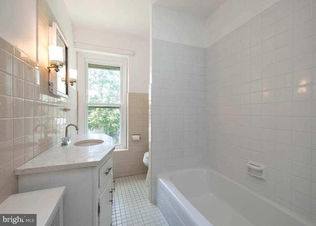 full bathroom featuring vanity, a bathing tub, toilet, tile patterned floors, and tile walls