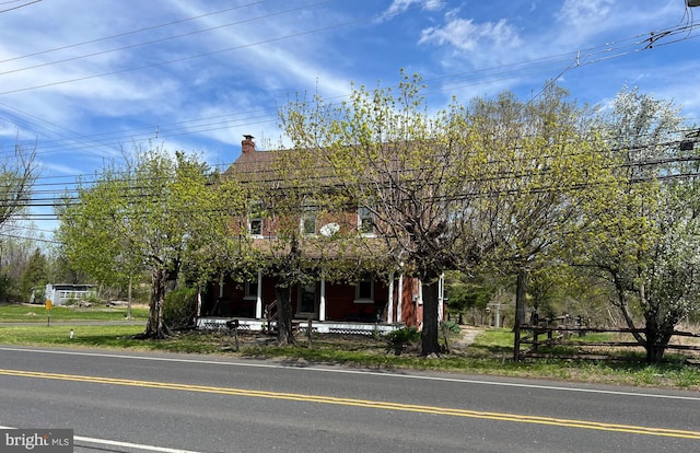 obstructed view of property featuring fence, covered porch, and a chimney