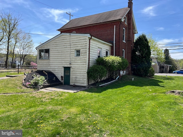 view of home's exterior featuring a yard, brick siding, and a chimney