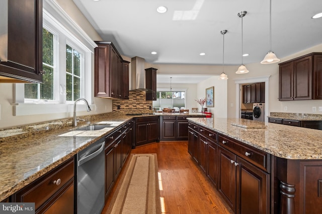 kitchen with wood finished floors, a sink, dishwasher, washer and dryer, and a kitchen island
