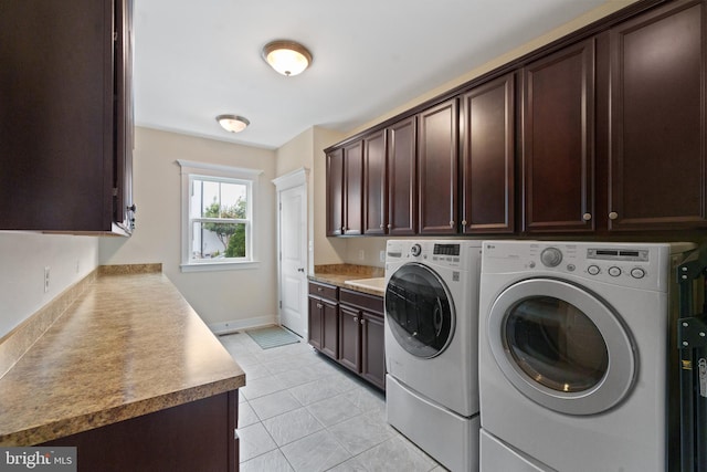 laundry room with washing machine and clothes dryer, cabinet space, light tile patterned flooring, and baseboards