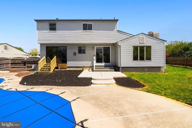 back of property featuring a yard, a fenced in pool, a chimney, and a fenced backyard