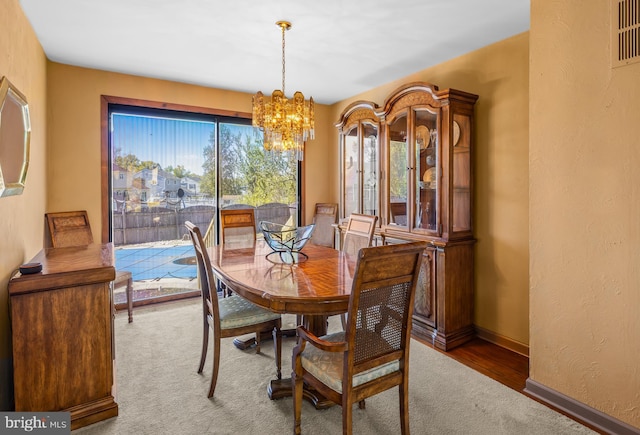 dining room featuring an inviting chandelier, baseboards, carpet flooring, and visible vents